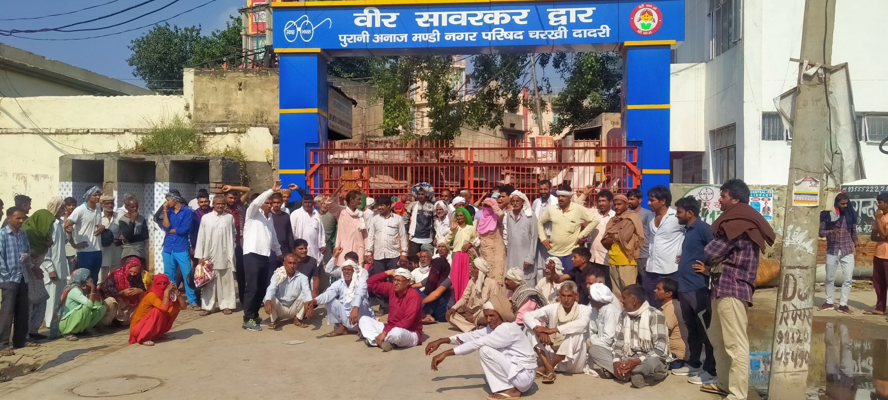 मंडी का गेट बंद करके बैठे किसान। मंडी का गेट बंद करके बैठे किसान।
