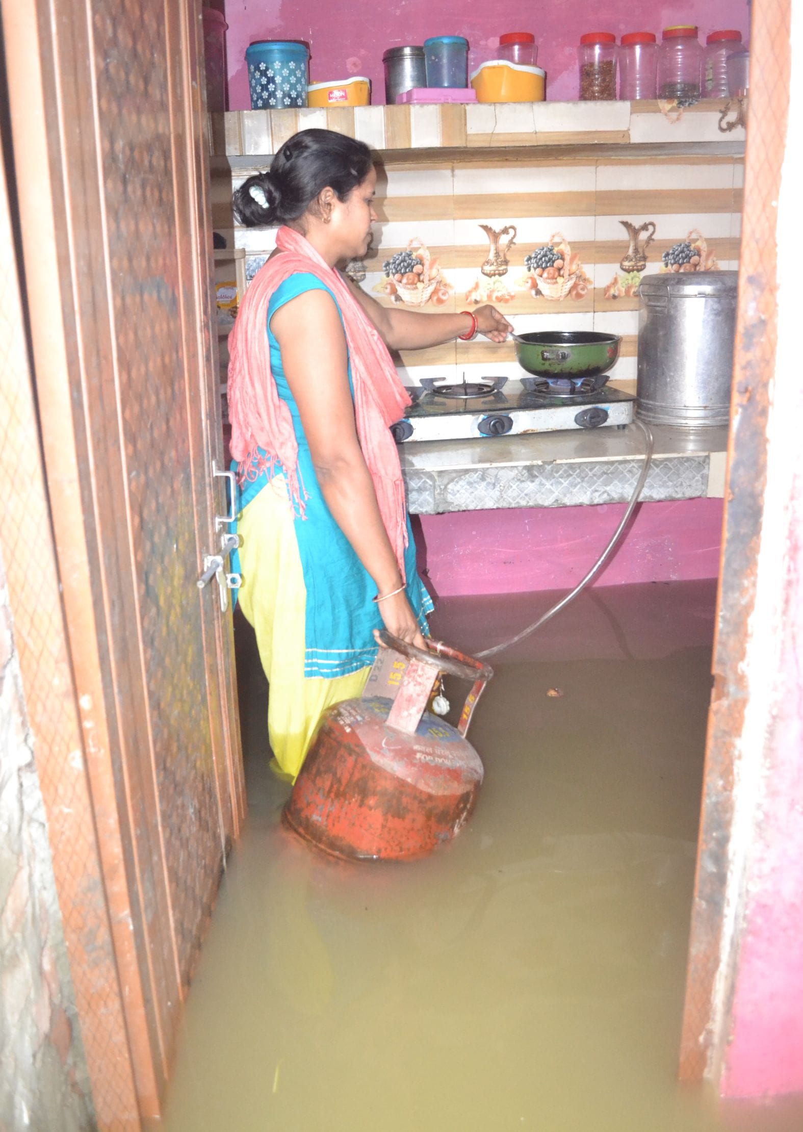 शहर के मोहल्ला विकास नगर में रसोई घर में भरे बारिश के पानी में खड़े होकर भोजन बनाती मोनी।(संवाद) वि शहर के मोहल्ला विकास नगर में रसोई घर में भरे बारिश के पानी में खड़े होकर भोजन बनाती मोनी।(संवाद) वि