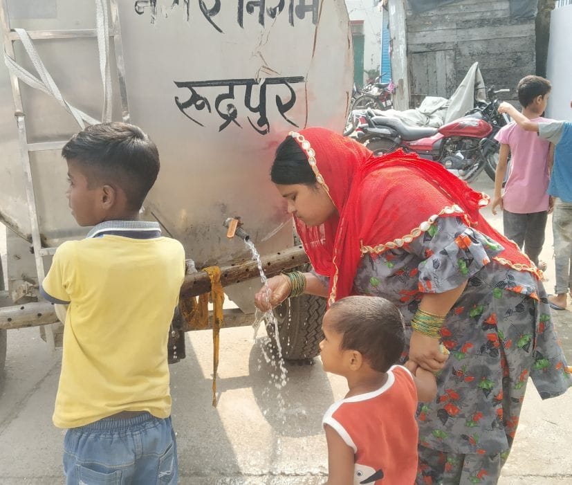 रुद्रपुर में पानी के टैंकर से पानी पीते आपदा पीड़ित।