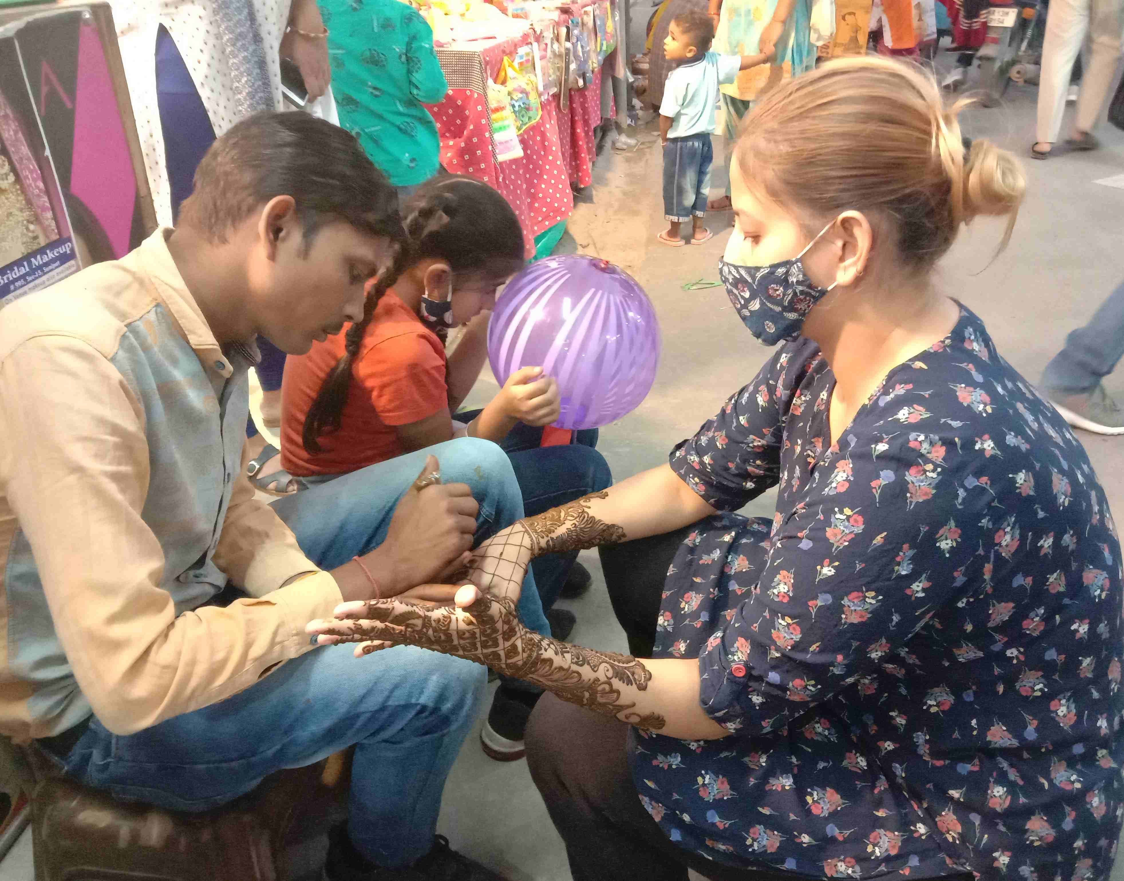 करवा चौथ पर्व को लेकर कच्चे क्वार्टर मार्केट में हाथों पर मेहंदी लगवाती युवती। संवाद करवा चौथ पर्व को लेकर कच्चे क्वार्टर मार्केट में हाथों पर मेहंदी लगवाती युवती। संवाद