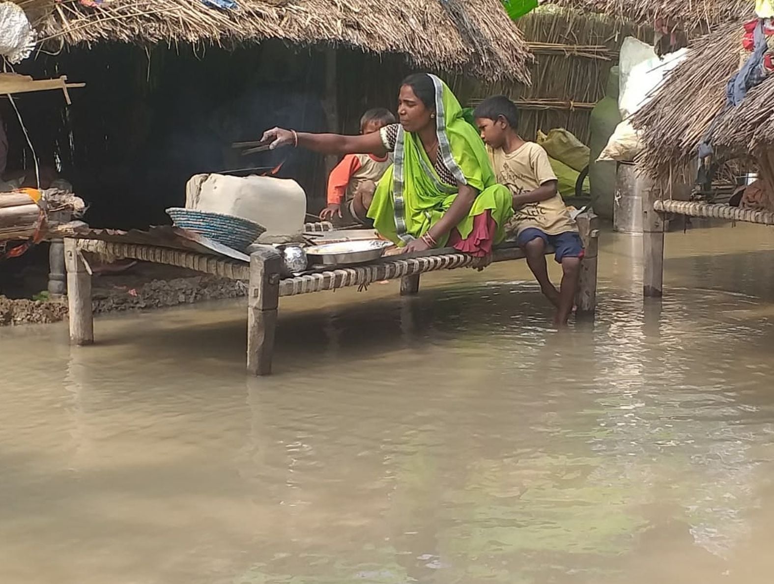 शमसाबाद के गांव कटरी तौफीक में बाढ़ का पानी भरने से चारपाई पर चूल्हा रखकर खाना बनाती महिला। संवाद
