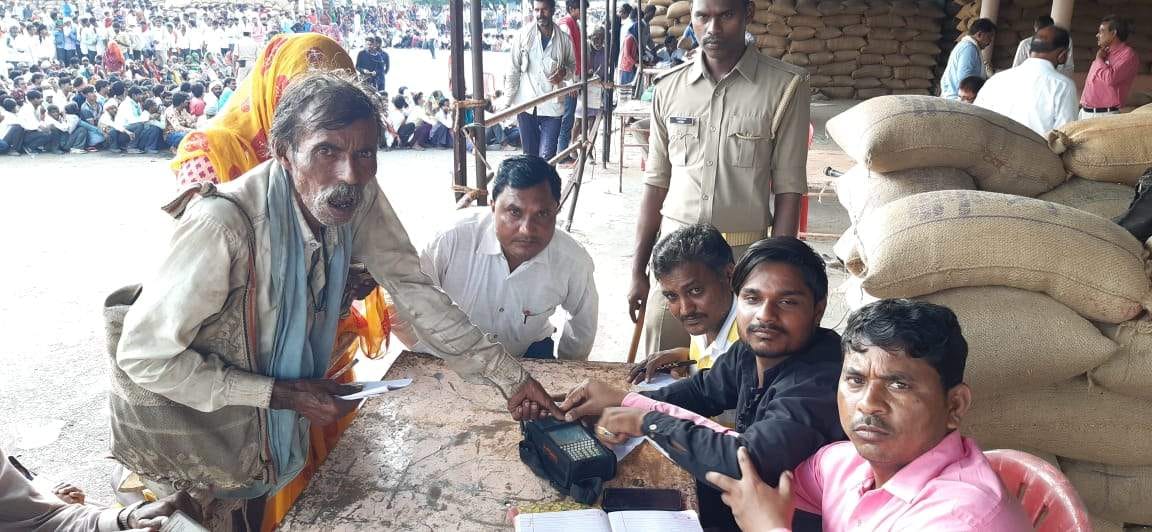 पॉस मशीन पर अंगूठा लगाते हुए किसान