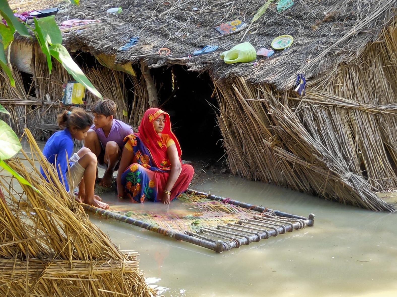 गांव भुड़रा के घरों में गंगा के बाढ़ का पानी भरने से चारपाई पर बैठ कर समय गुजारता परिवार। संवाद गांव भुड़रा के घरों में गंगा के बाढ़ का पानी भरने से चारपाई पर बैठ कर समय गुजारता परिवार। संवाद