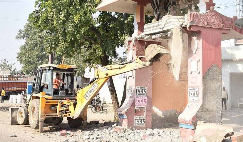 रुद्रपुर के एनएच-74 के किनारे धार्मिक स्थल के मुख्य द्वार को तोड़ती जेसीबी।