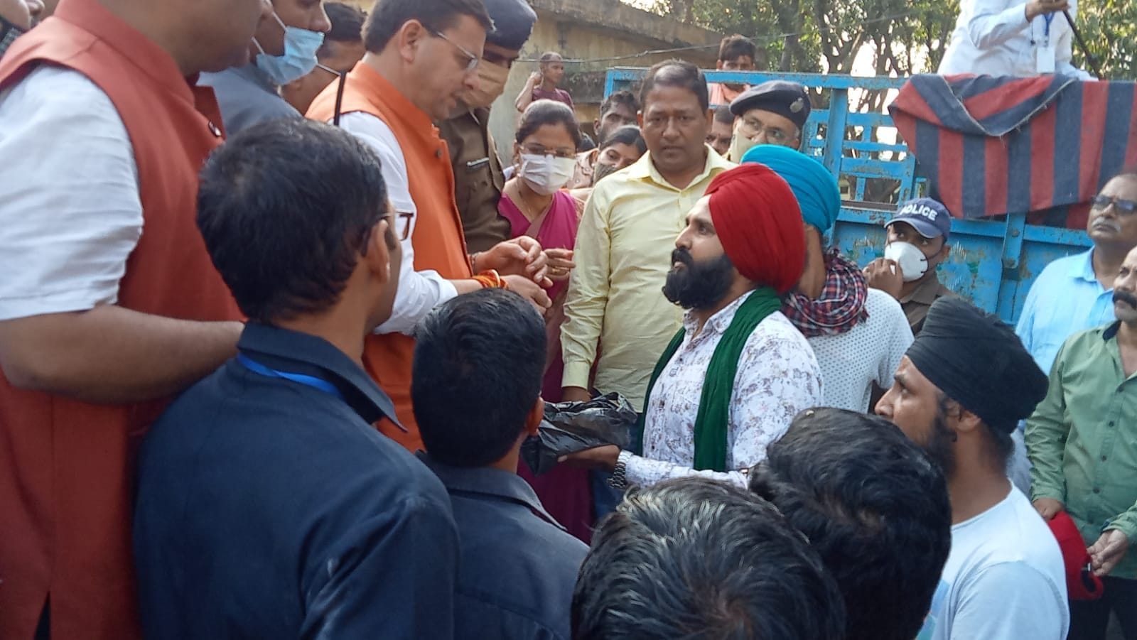 खटीमा मंडी समिति परिसर में अतिवृष्टि से खराब धान का सैंपल सीएम धामी को दिखाते किसान।