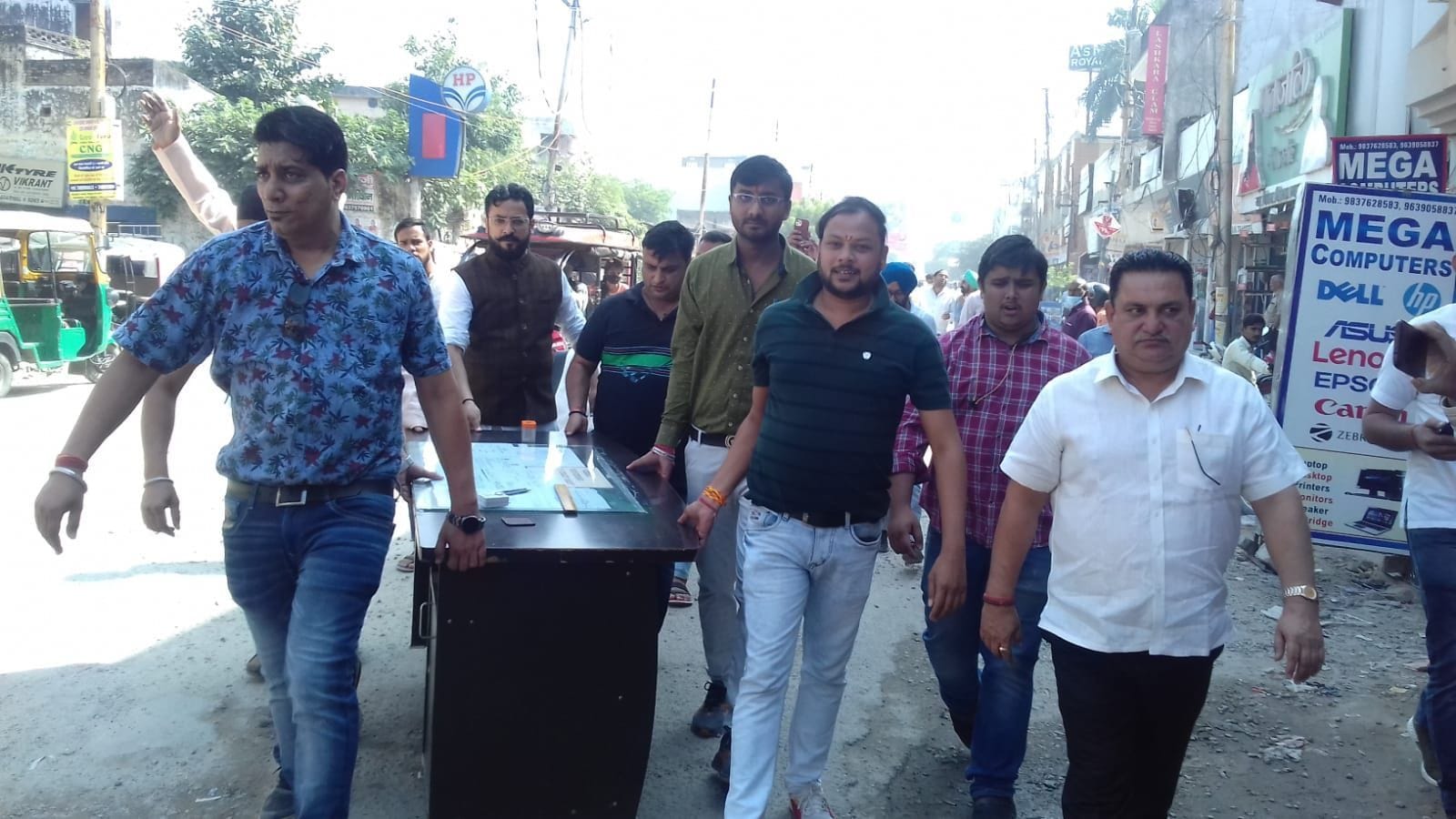 बिल्डर के कार्यालय से सामान बाहर लाते व्यापारी।