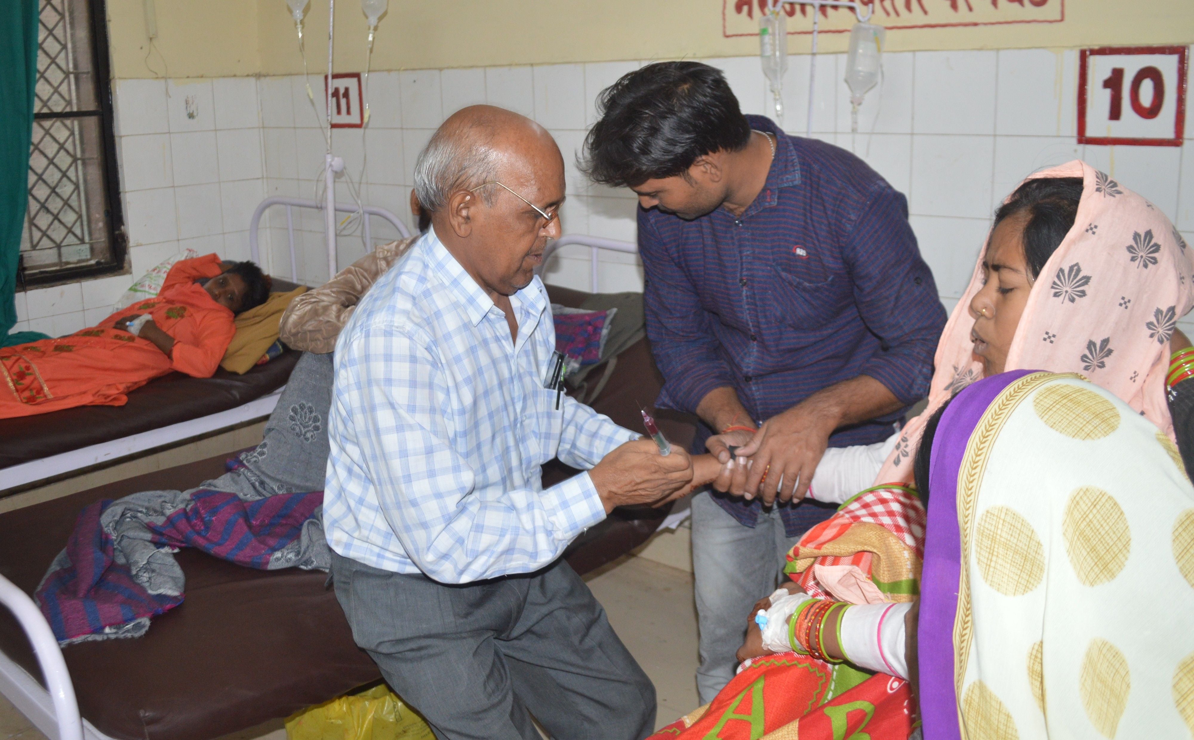 हाथरस : बागला जिला अस्पताल में भर्ती बुखार के मरीज के खून का नमूना लेते कर्मचारी।    संवाद