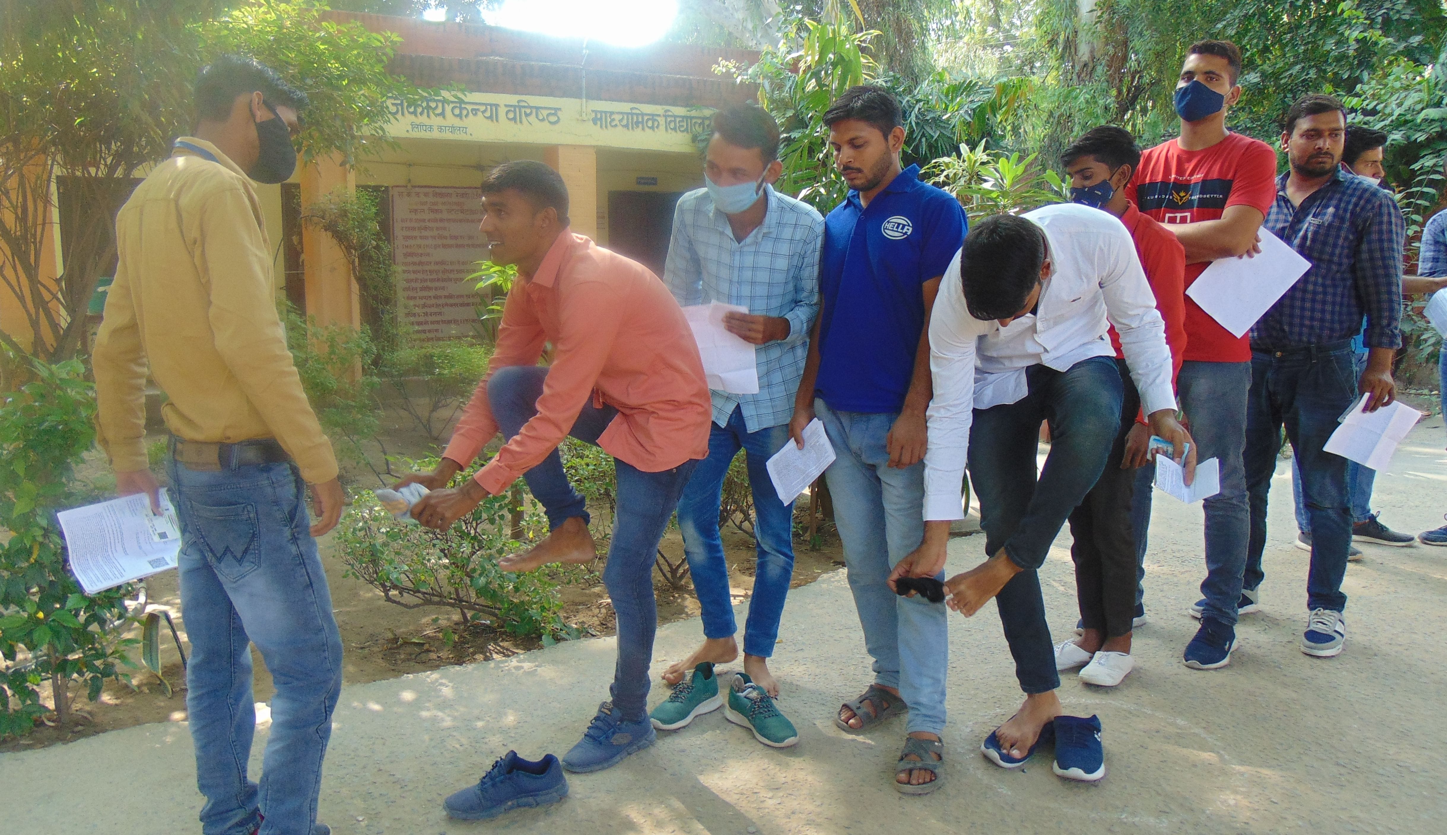 परीक्षार्थियों के जूते उतरवाकर जांच करता ड्यूटी पर तैनात कर्मचारी। संवाद परीक्षार्थियों के जूते उतरवाकर जांच करता ड्यूटी पर तैनात कर्मचारी। संवाद