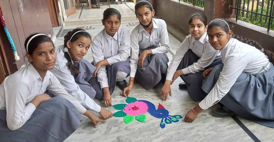 शामली के के पब्लिक स्कूल में रंगोली बनाती छात्राएं