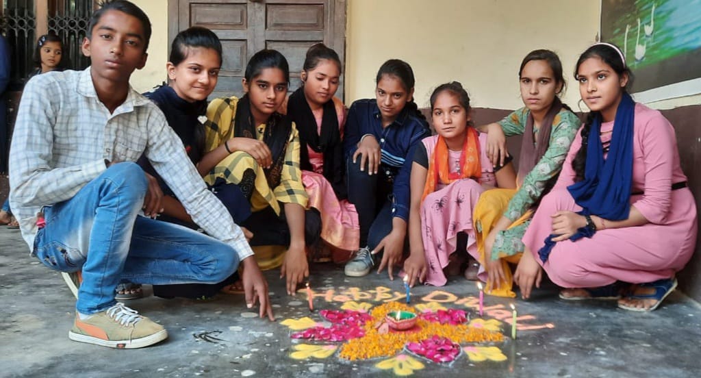 पुरकाजी के मदर लैंड पब्लिक स्कूल में रंगोली बनाते बच्चे