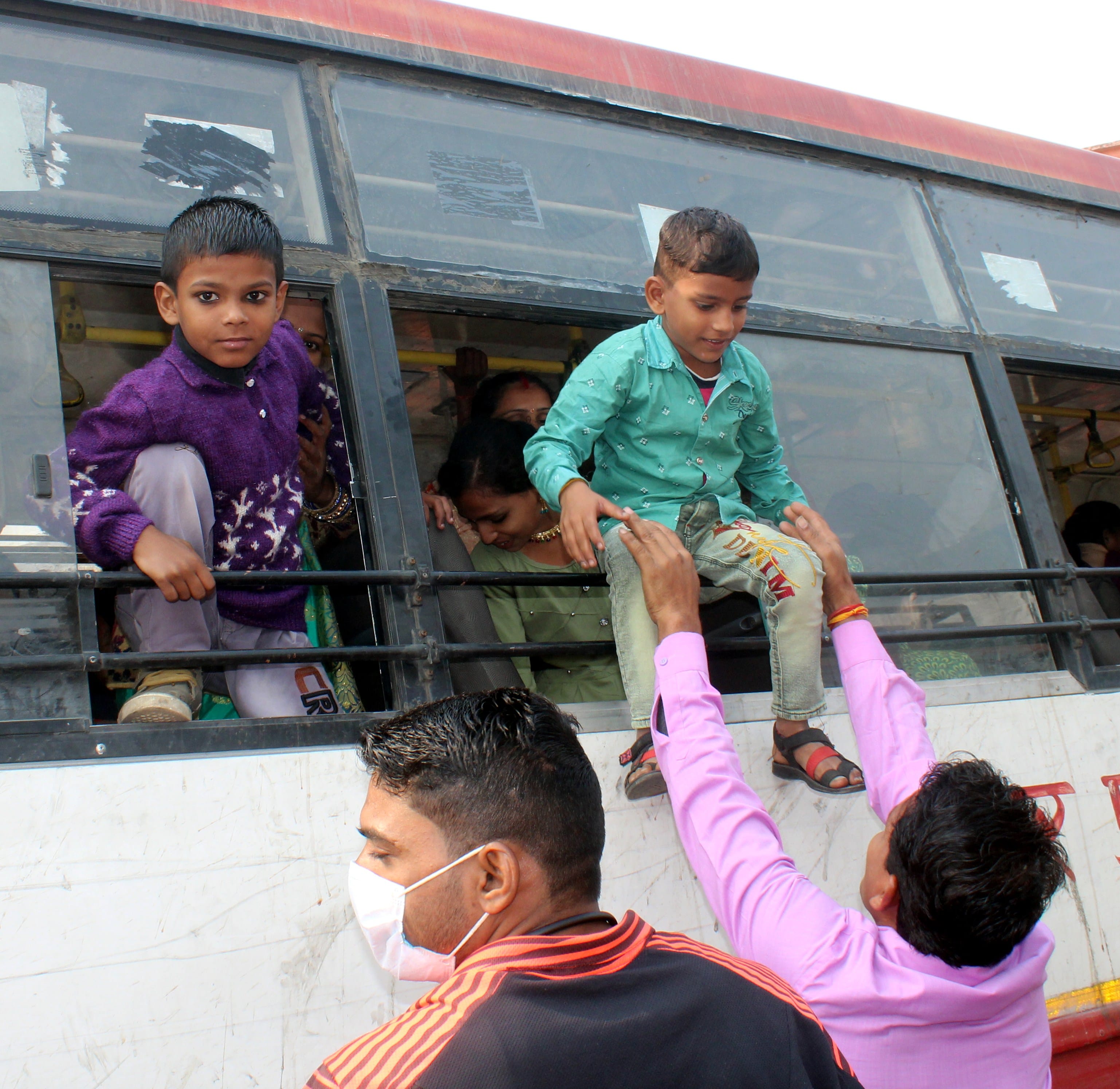 अमरोहा में बस में भीड़ के चलते खिड़की के सहारे बच्चों को उतारते परिजन।