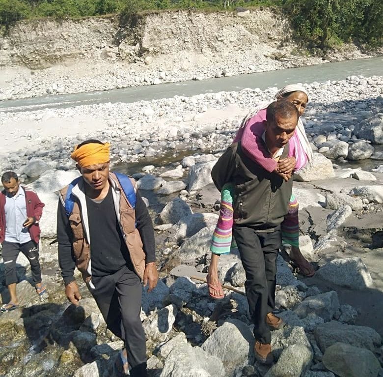 बुजुर्ग महिला को पीठ में डोहकर अस्पताल पहुंचाते ग्रामीण। बुजुर्ग महिला को पीठ में डोहकर अस्पताल पहुंचाते ग्रामीण।