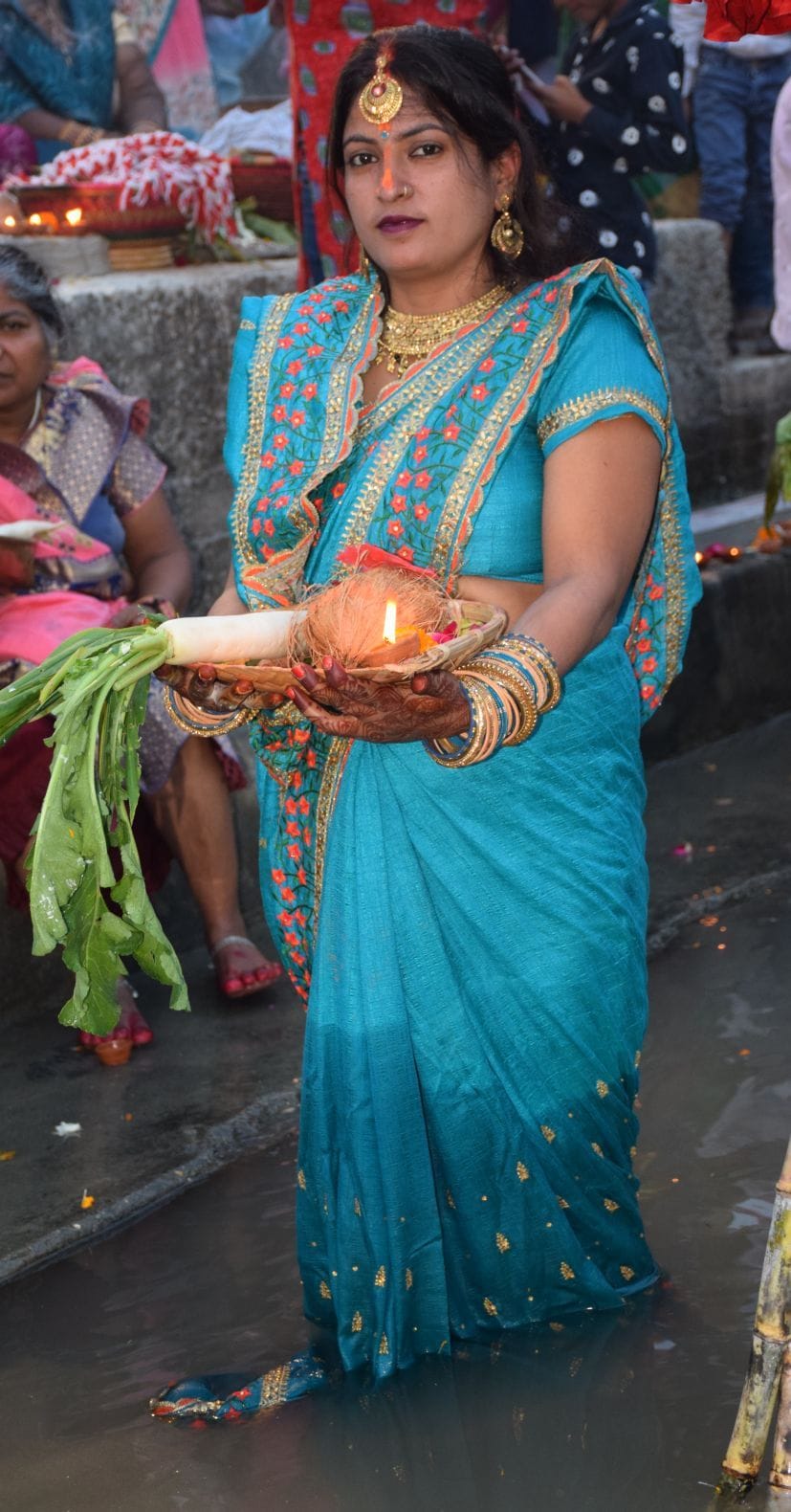 रुद्रपुर छठ पूजा घाट पर पानी में खड़े होकर डूबते सूर्य को अर्घ्य देती महिला।