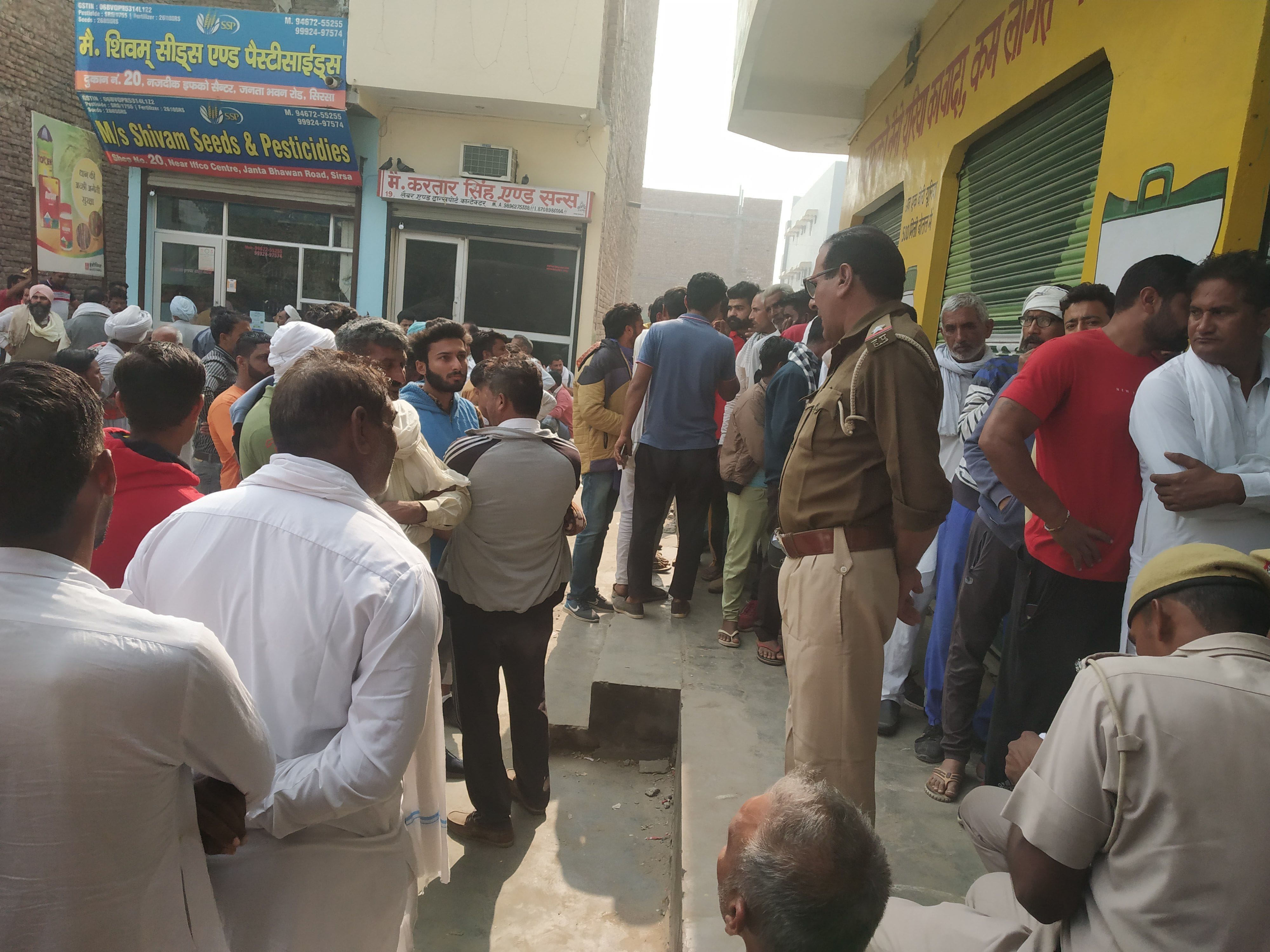 डीएपी लेने के लिए केंद्र के बाहर लाइन में लगे किसान और तैनात पुलिस बल। 