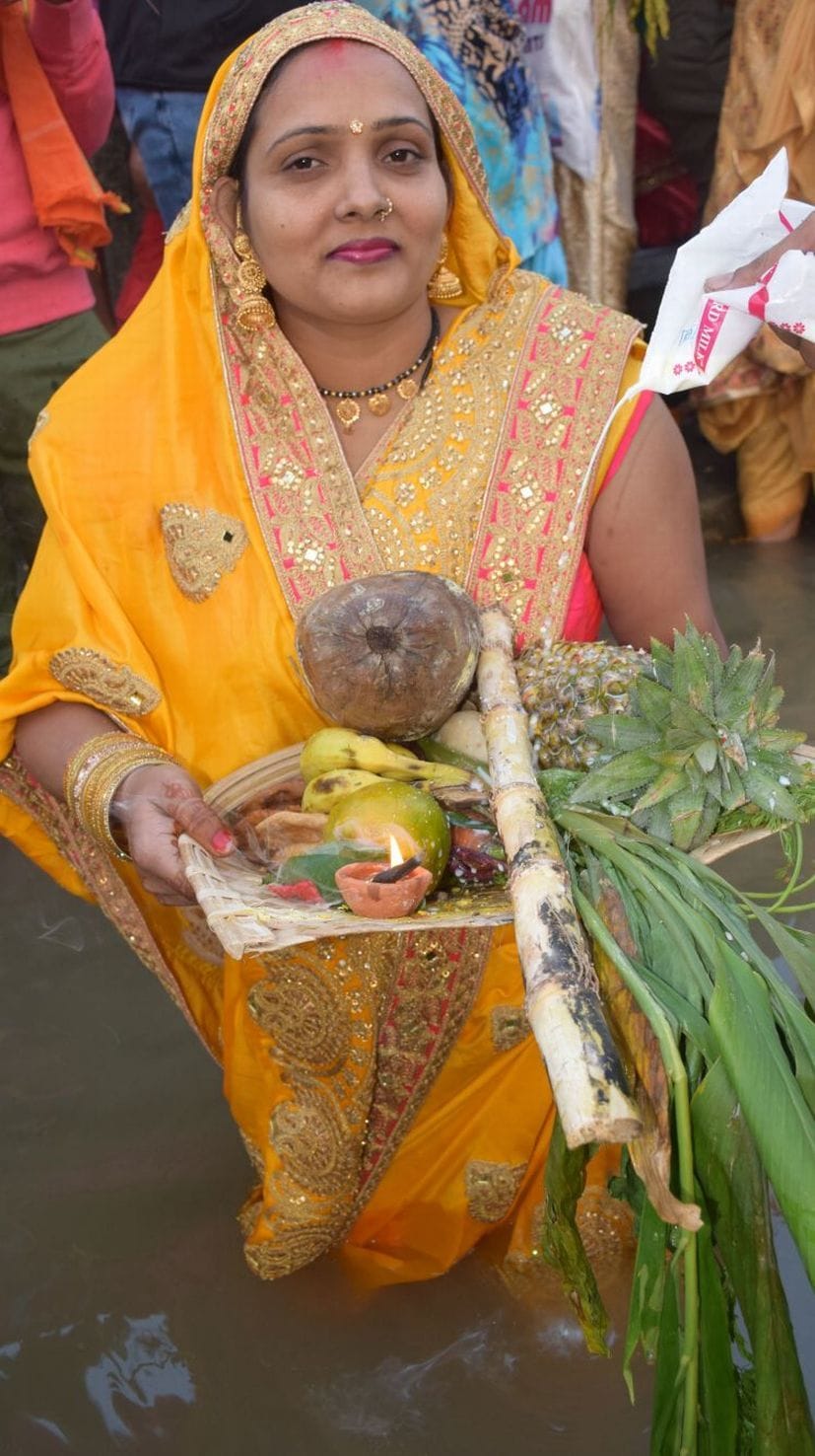 रुद्रपुर छठ पूजा घाट पर उगते सूर्य को अर्घ्य देती महिला।