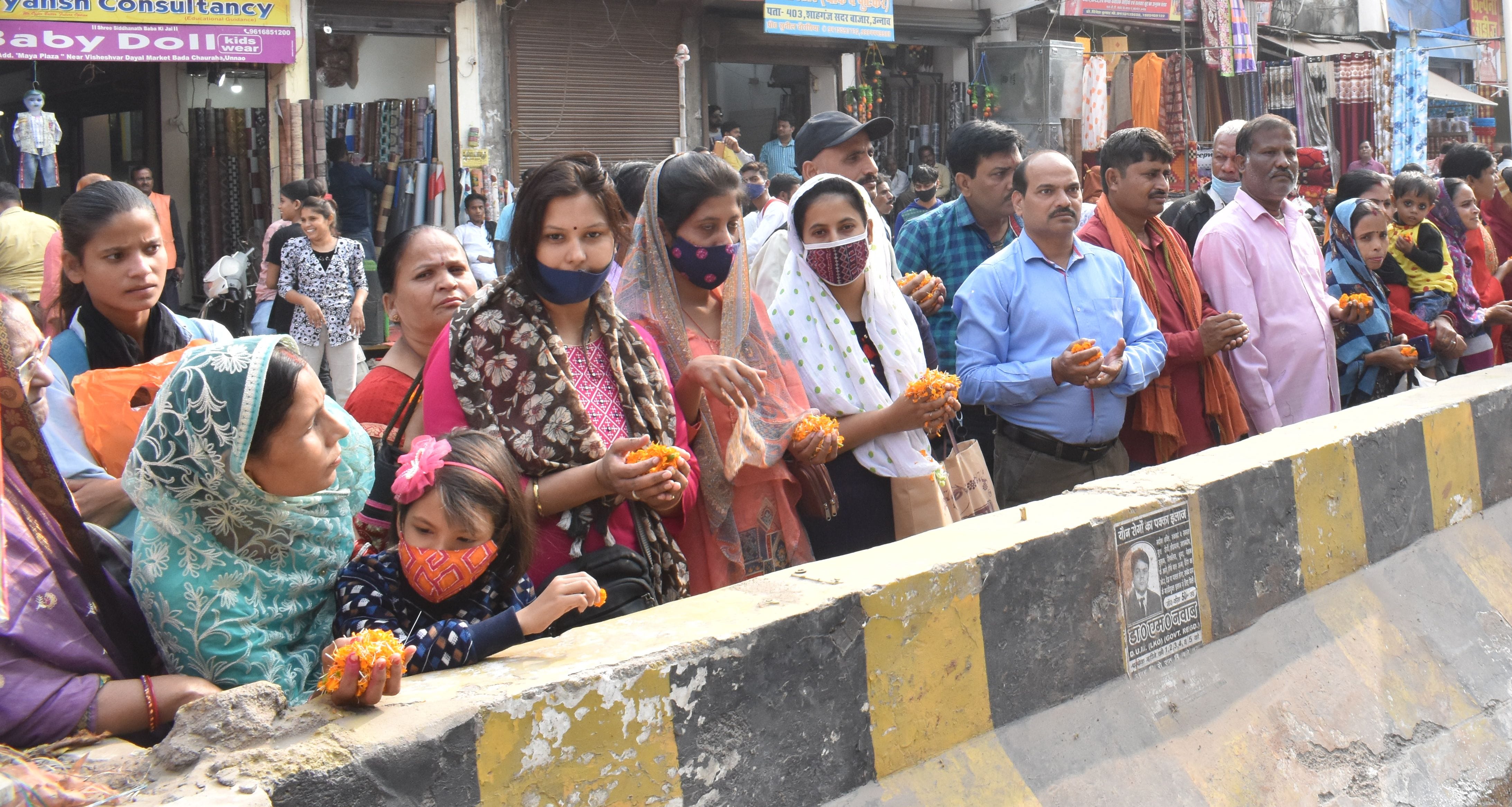 बड़ा चौराहा पर अन्नपूर्णा देवी पुर्नस्थापना यात्रा के स्वागत के लिए हाथ में फूल लेकर खड़ी महिला?