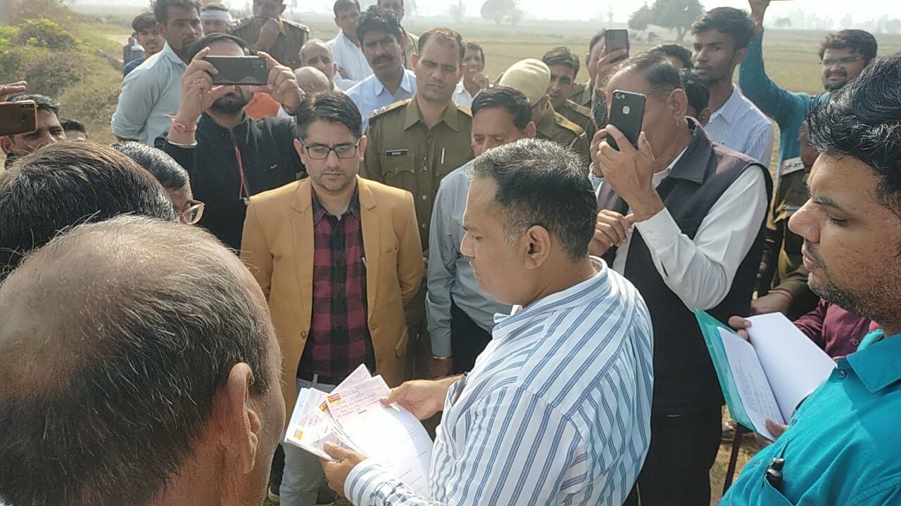 नायब तहसीलदार खेतों में पाइप लाइन डालने के लिए निर्देश देते हुए 