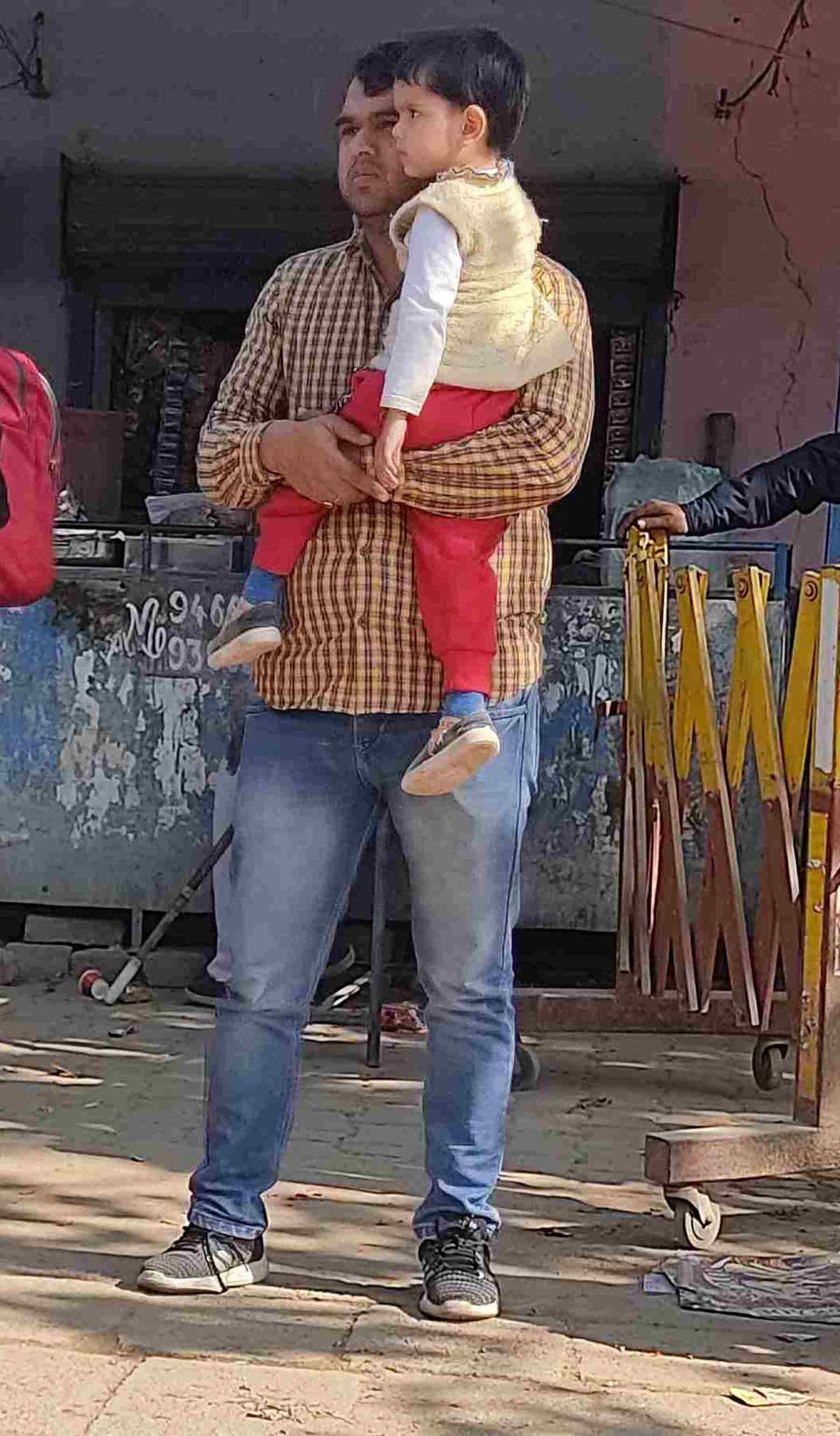 परीक्षा केंद्र के बाहर अपने बच्चे को गोद में लेकर खड़ा व्यक्ति। संवाद परीक्षा केंद्र के बाहर अपने बच्चे को गोद में लेकर खड़ा व्यक्ति। संवाद