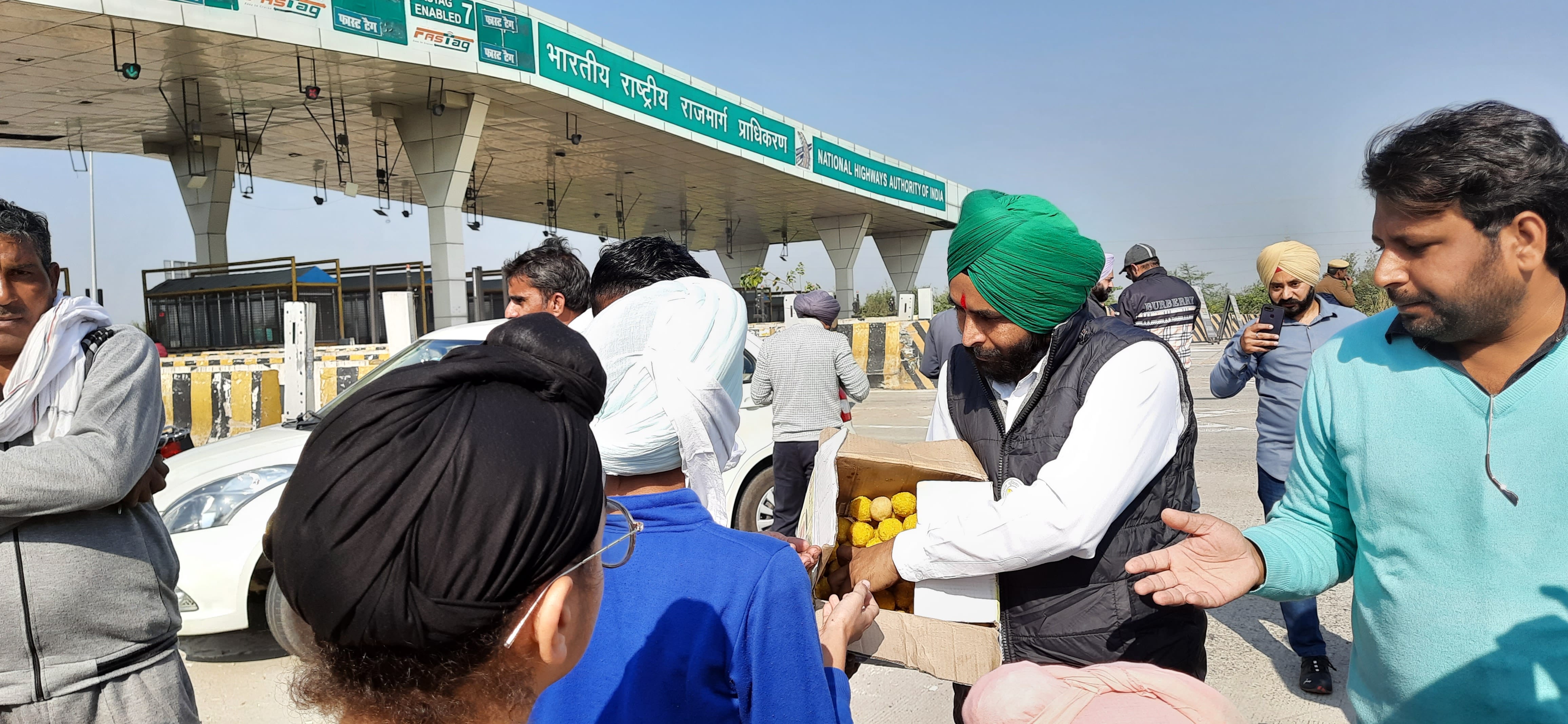 मिल्क माजरा टोल प्लाजा पर लोगों को लड्डू बांटते किसान। संवाद मिल्क माजरा टोल प्लाजा पर लोगों को लड्डू बांटते किसान। संवाद