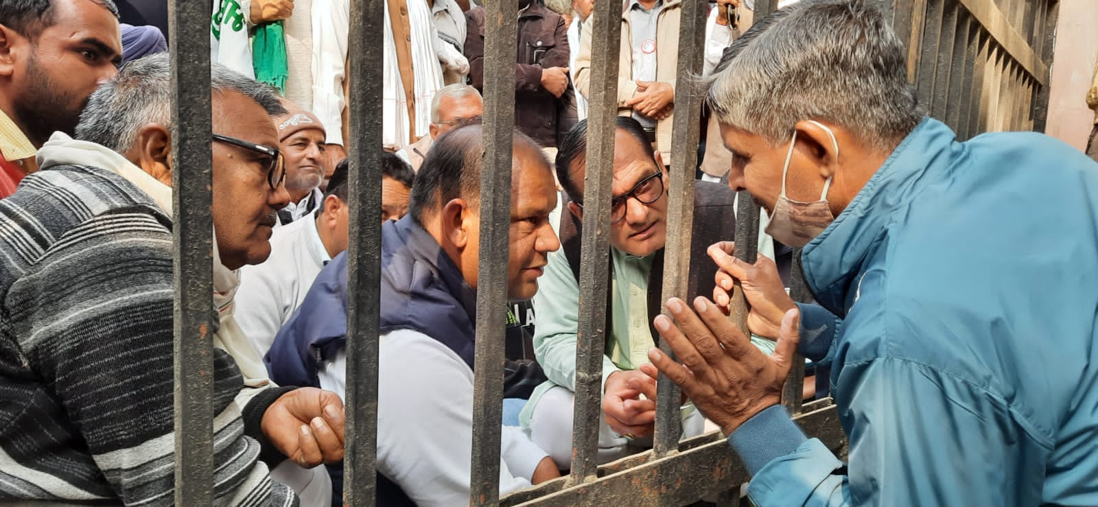 गेट की दूसरी तरफ बैठे किसानों से बातचीत करते सीआईडी के कर्मचारी।  संवाद