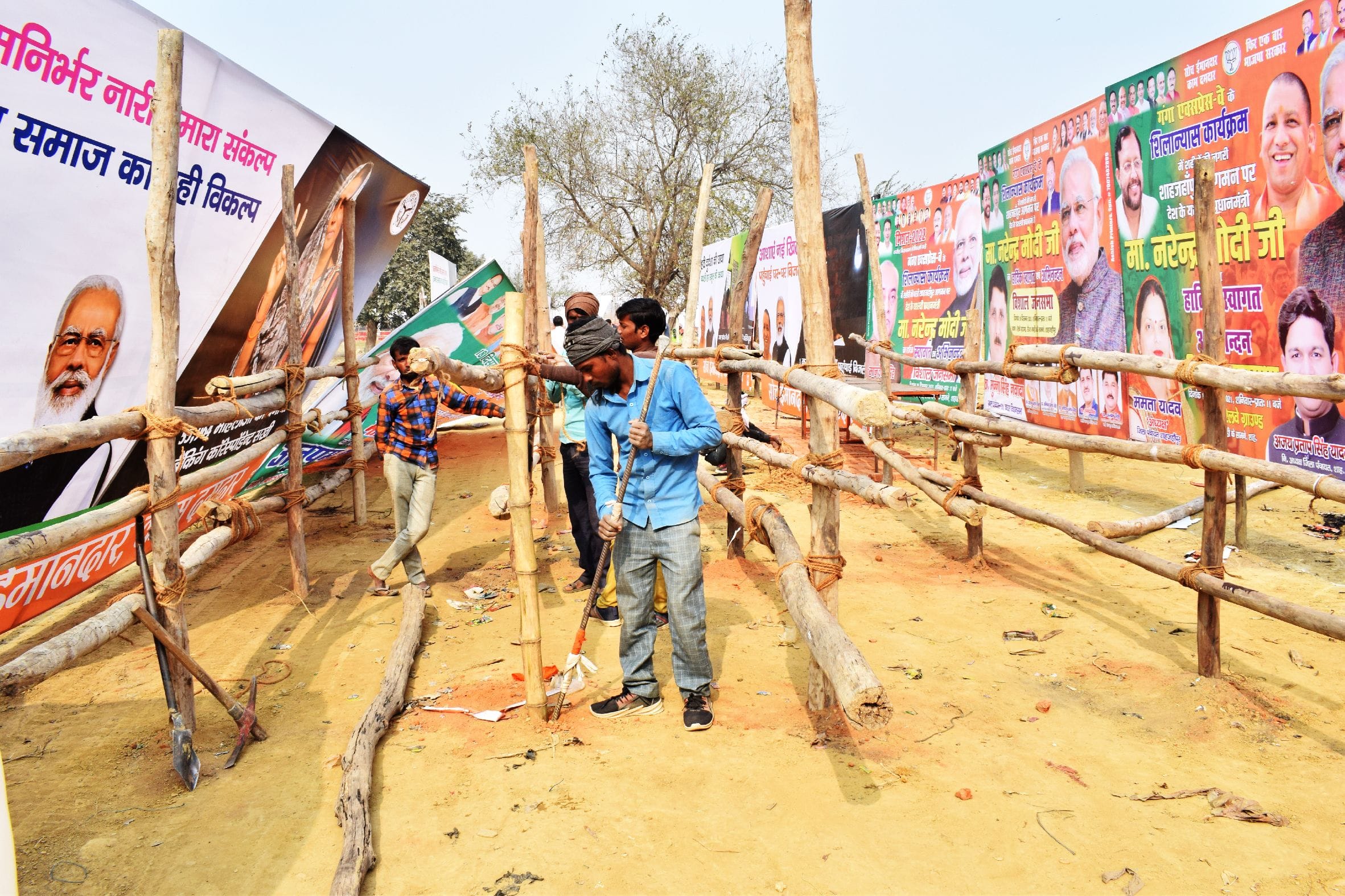 प्रधानमंत्री की जनसभा के लिए एक प्रवेश द्वार पर बल्लियों की बैरीकेडिंग करते मजदूर। संवाद