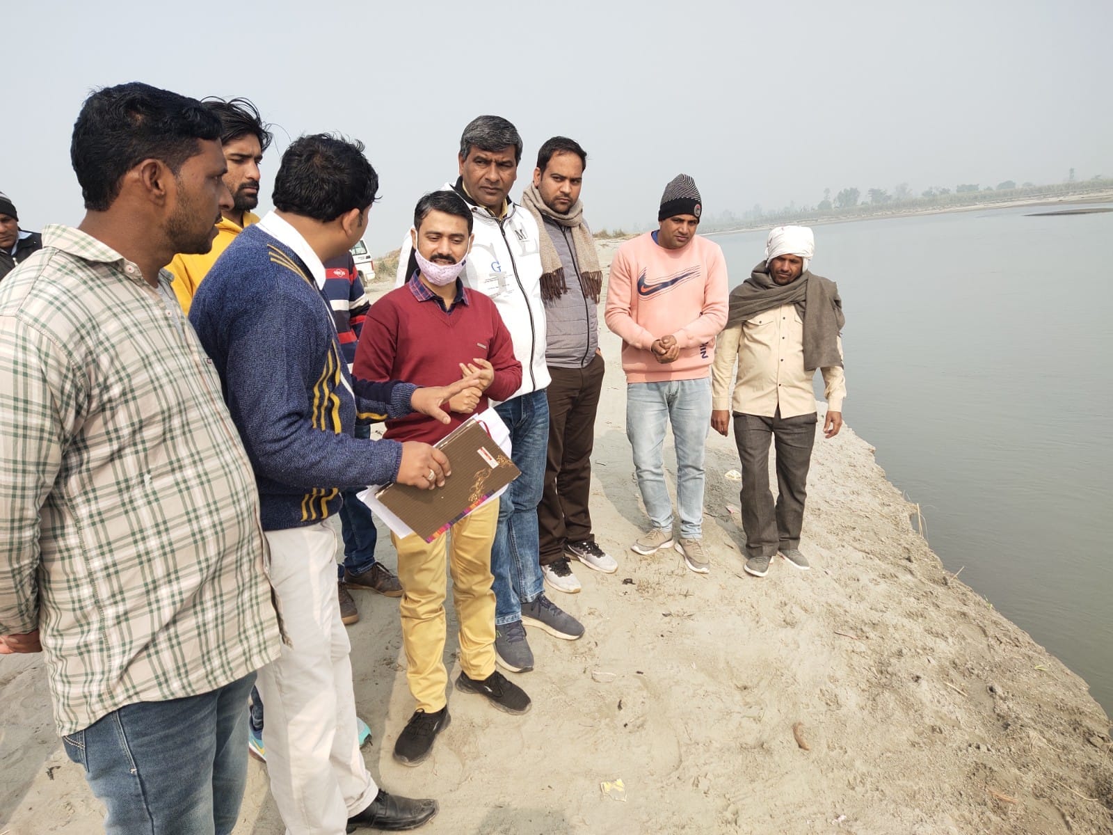 नदी किनारे खड़े होकर निर्देश देते हुए अधिकारी। नदी किनारे खड़े होकर निर्देश देते हुए अधिकारी।