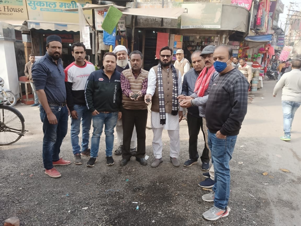 सरास में बनते ही टूटी सड़क पर बिखरी बजरी को दिखाता मार्केट के व्यापारी सरास में बनते ही टूटी सड़क पर बिखरी बजरी को दिखाता मार्केट के व्यापारी