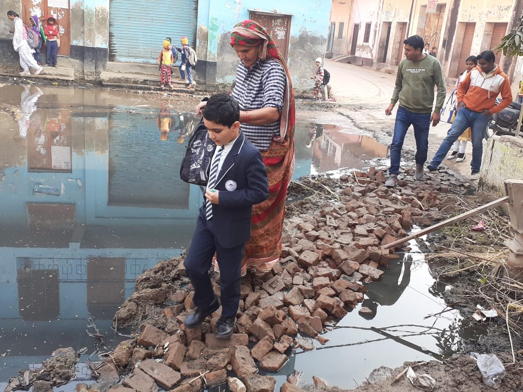 बड़ौत के मलकपुर गांव में दूषित पानी से भरी गली से छोटे बच्चें का स्कूल छोड़ने जाती बुजुर्ग महिला। बड़ौत के मलकपुर गांव में दूषित पानी से भरी गली से छोटे बच्चें का स्कूल छोड़ने जाती बुजुर्ग महिला।