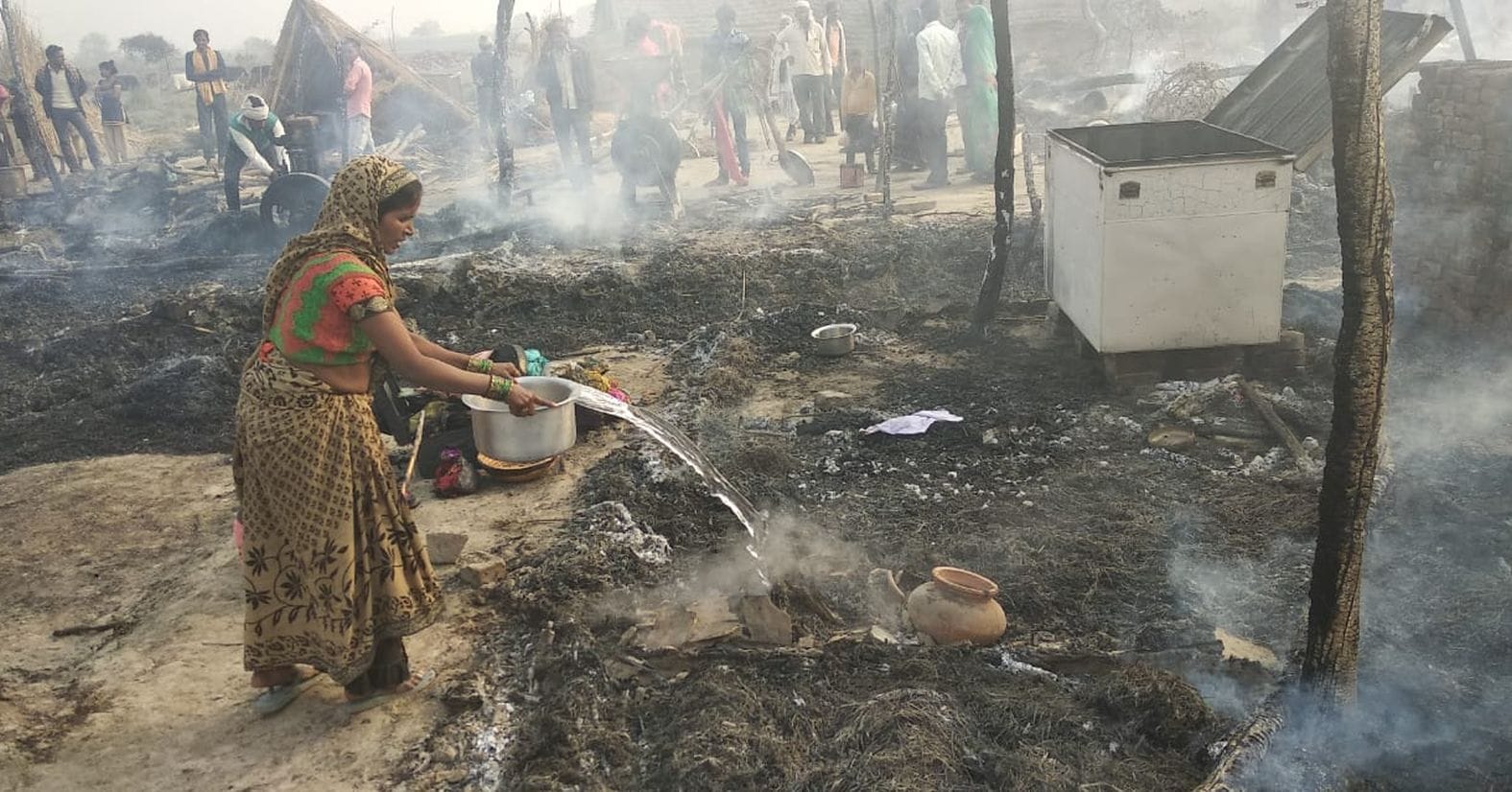 कटरी कंचनपुर में लगी आग को बुझाने के लिए पानी डालती महिला। संवाद कटरी कंचनपुर में लगी आग को बुझाने के लिए पानी डालती महिला। संवाद