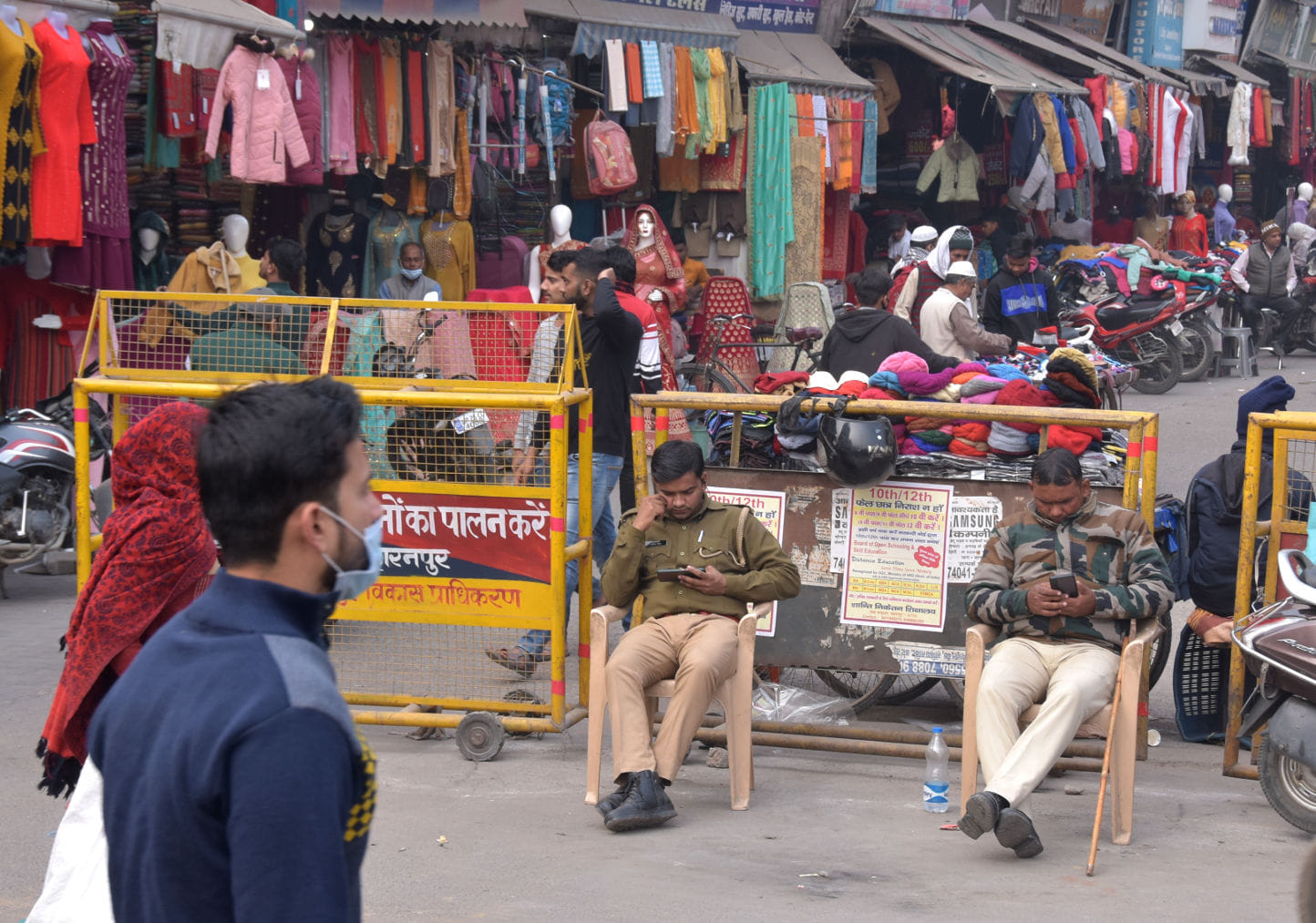 श्रीराम चौक पर बिना मास्क के बैठे पुलिस कर्मी मास्क लगा कर जाते लोग