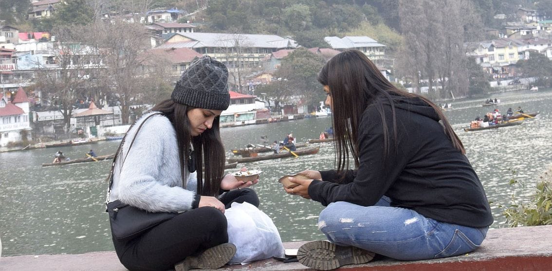 नैनीताल में नैनीझील के किनारे बैठकर मौजमस्ती करते पर्यटक।