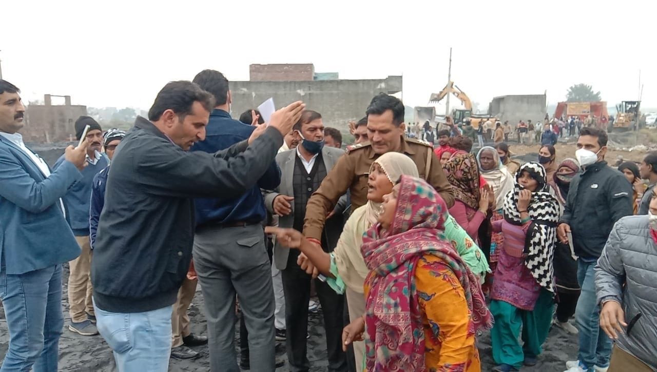 बहालगढ़ के पास कब्जा कार्रवाई के दौरान बहस कर रहीं महिलाओं को हाथ जोड़कर शांत कराता अधिकारी। संव?