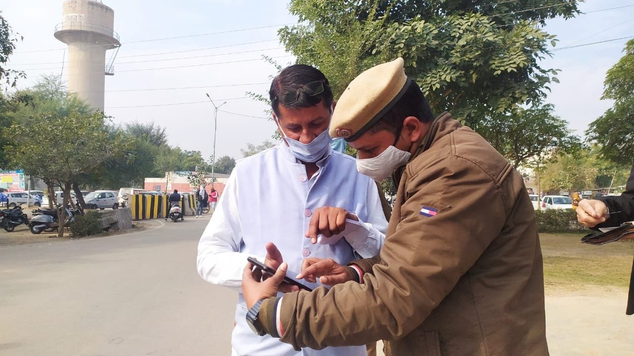 लघु सचिवालय के मुख्य गेट पर आने वालों के टीकाकरण प्रमाण पत्र जांचता पुलिस कर्मचारी।
