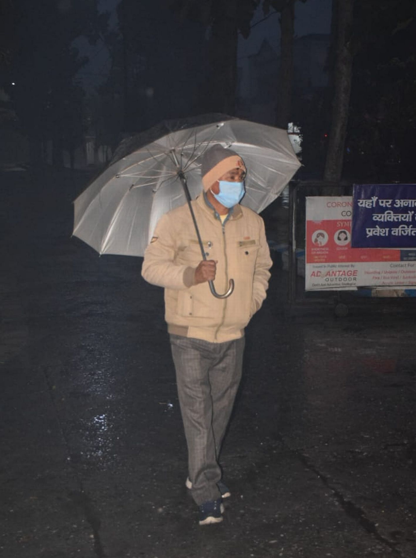 Seseorang lewat dengan payung untuk menghindari hujan di Rudrapur.