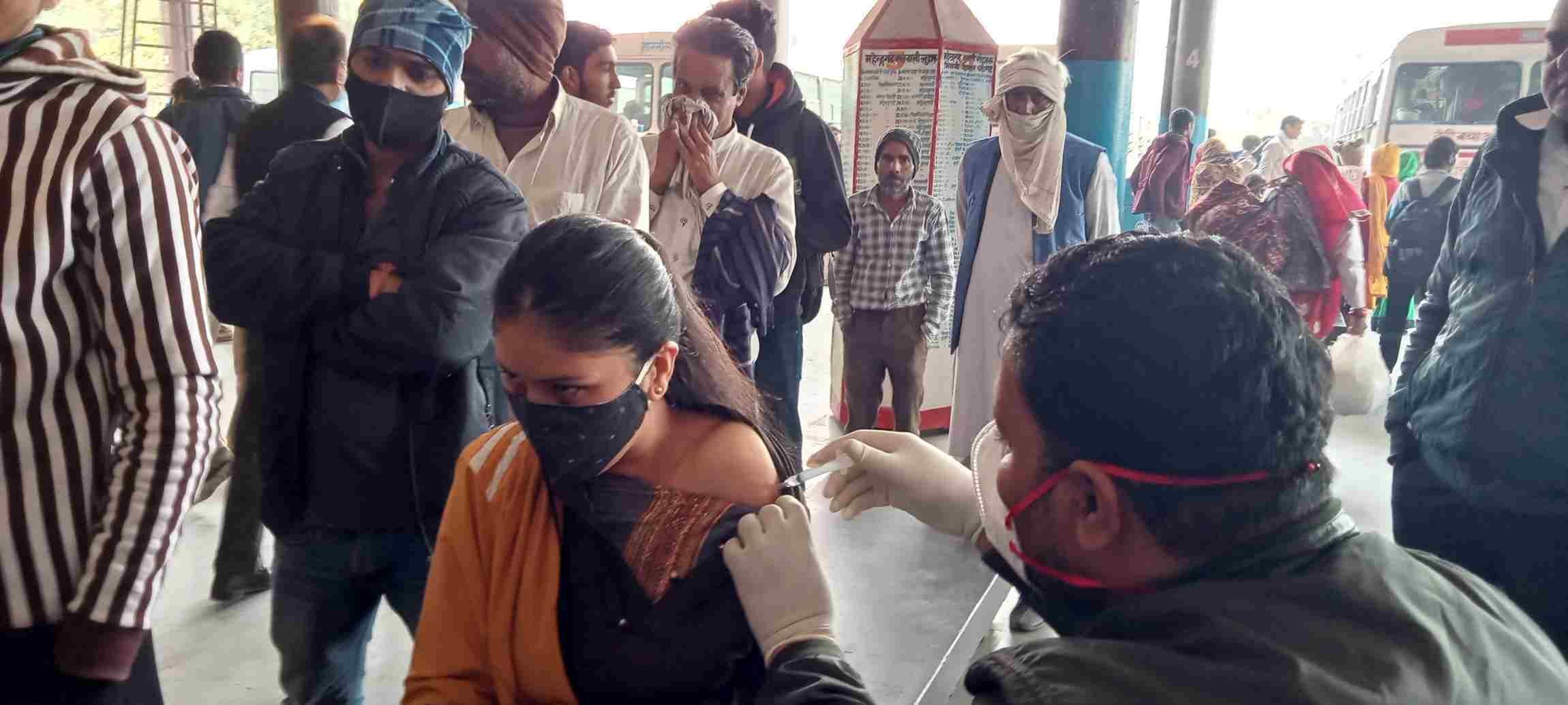  बस स्टैंड पर टीका लगवाती छात्रा। संवाद
