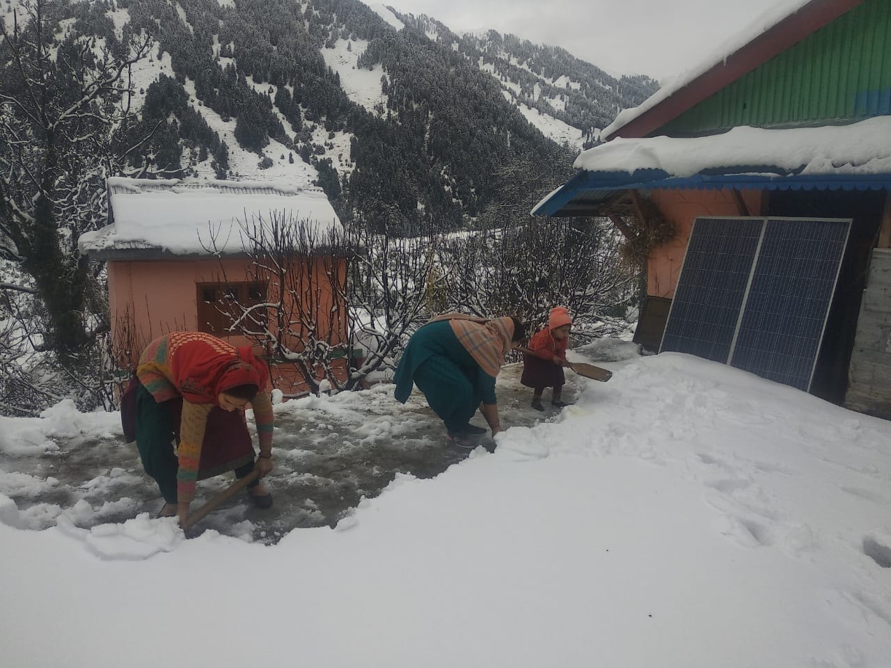 ढग्गर में घर की छत से बर्फ हटाती महिलाएं