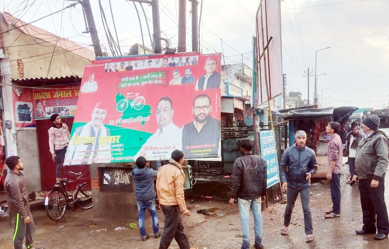पुवायां में होर्डिंग उतारते नगर पालिका कर्मचारी