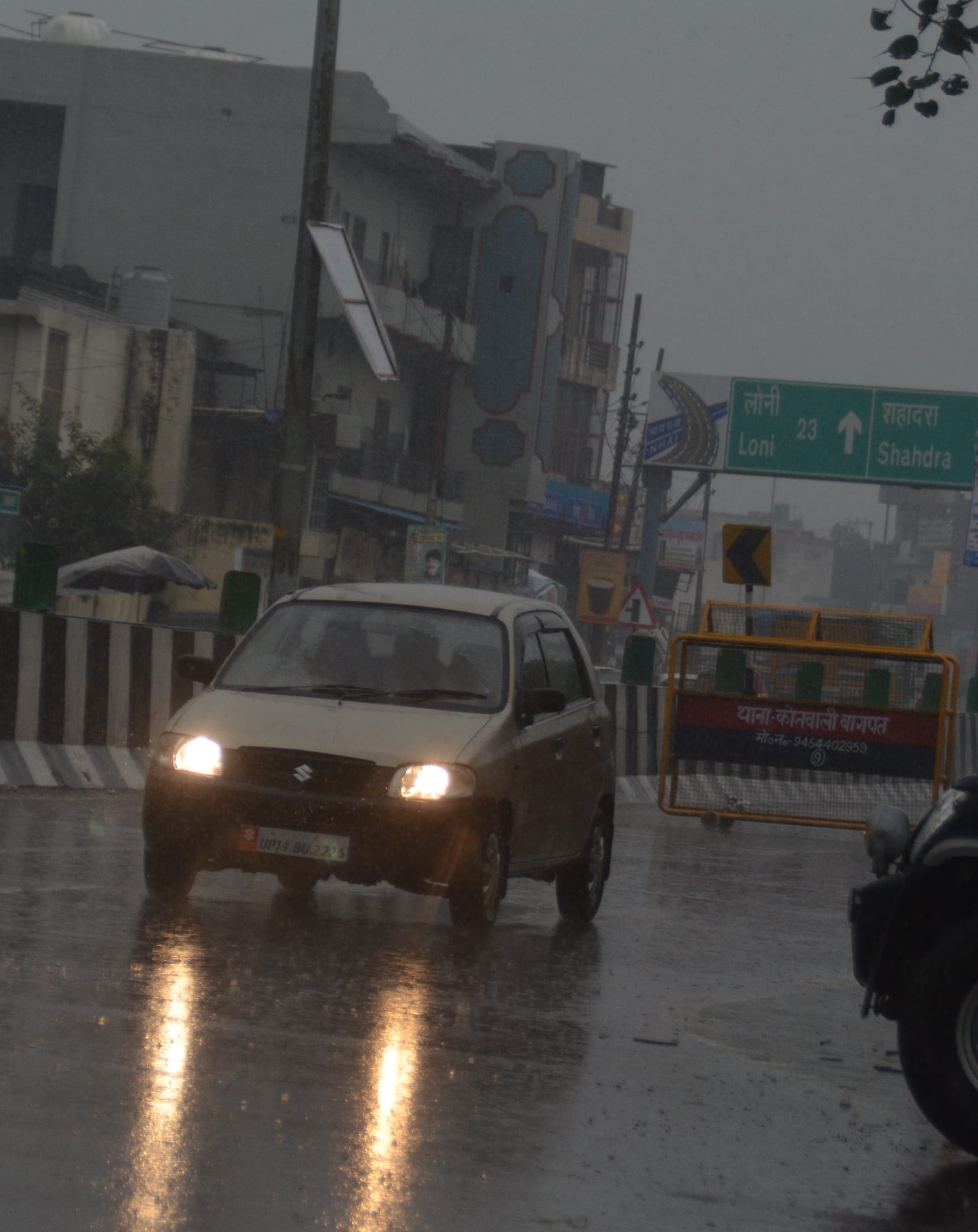 बागपत में बारिश् के दौरान कार की लाइट जलाकर जाते हुए