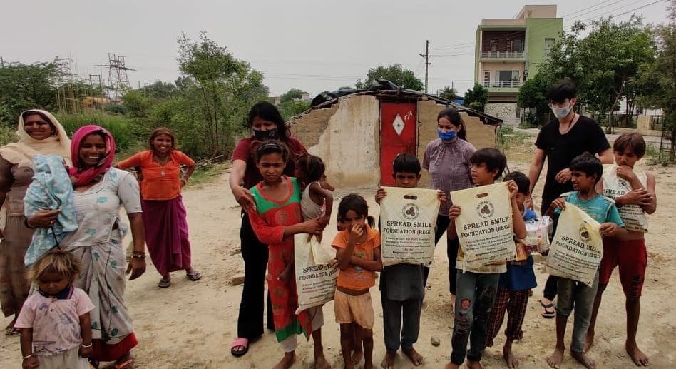 कोरोना महामारी के समय स्प्रेड स्माइल फाउंडेशन के सदस्य जरूरतमंदों को खाद्य सामग्री वितरित करते 