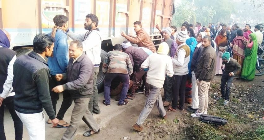 घटना स्थल में ट्रक के पहियों की नीचे से पारुल का शव निकालते ग्रामीण। संवाद घटना स्थल में ट्रक के पहियों की नीचे से पारुल का शव निकालते ग्रामीण। संवाद