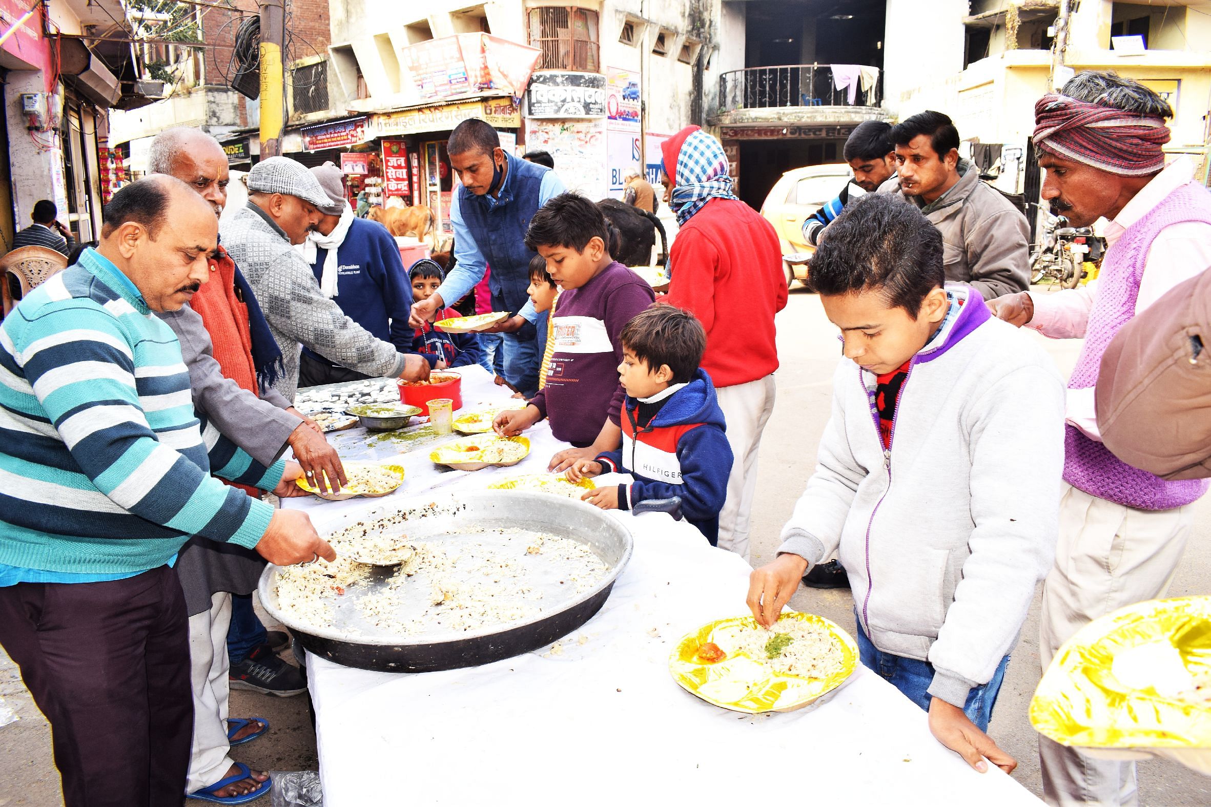 Orang-orang makan khichdi di Bhandara yang diselenggarakan di Khirni Bagh di Makar Sankranti di Shahjahanpur. percakapan Orang-orang makan khichdi di Bhandara yang diselenggarakan di Khirni Bagh di Makar Sankranti di Shahjahanpur. percakapan