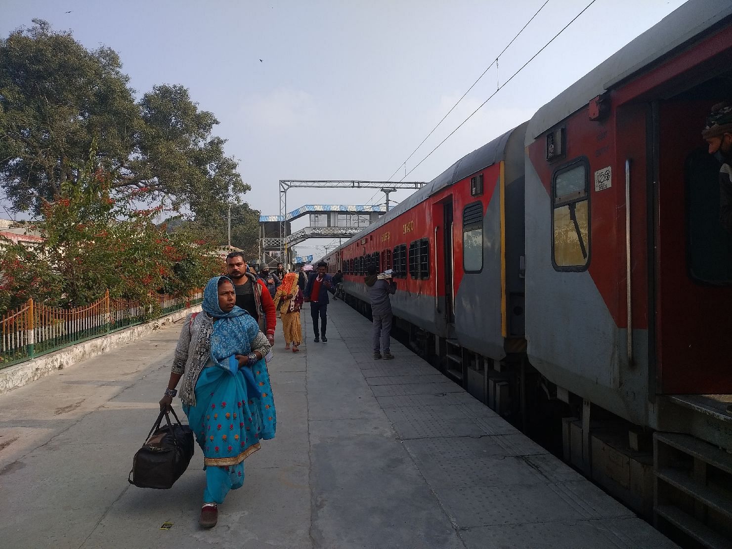 Penumpang tanpa masker akan naik kereta di stasiun kereta api Shahjahanpur