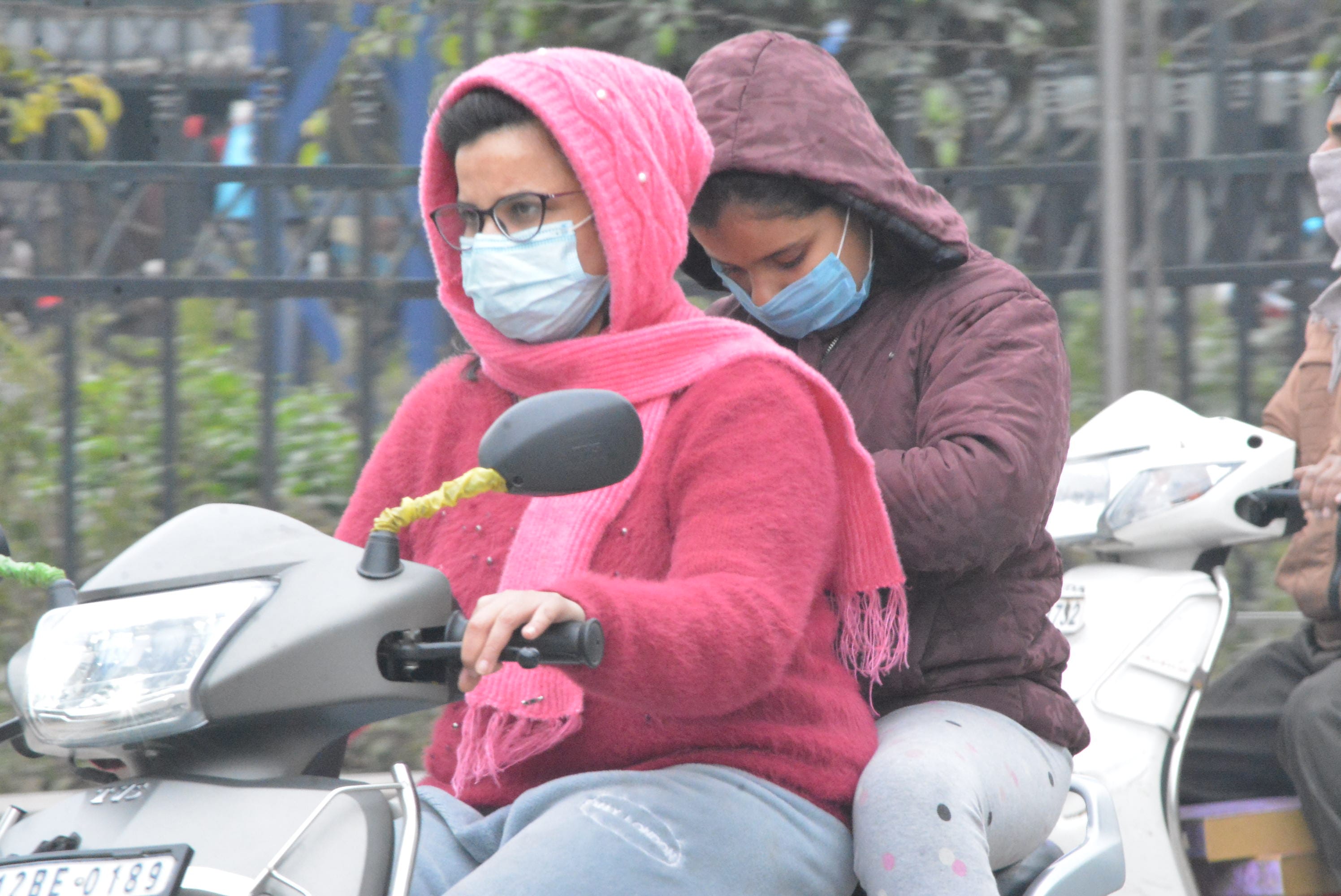 कडाके की ठंड से बचाव के लिए ऊनी मफलर में  महावीर चौक से गुजरती स्कूटी सवार।