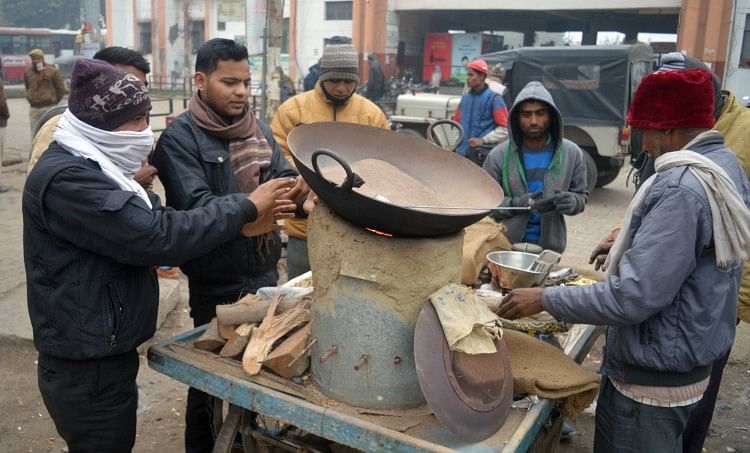 फो रोडवेज बस स्टेशन के सामने मूंगफली के ठेले पर भट्ठी में हाथ सेंकते लोग।