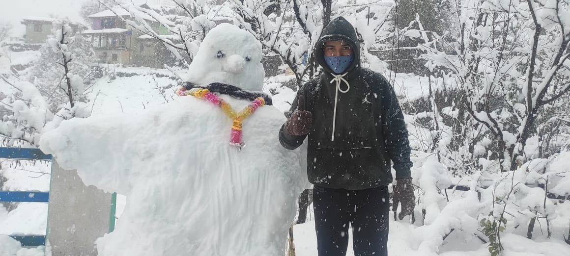 डुग्गन के भुलड़ी गांव में स्नो मैन के साथ खड़ा युवक डुग्गन के भुलड़ी गांव में स्नो मैन के साथ खड़ा युवक