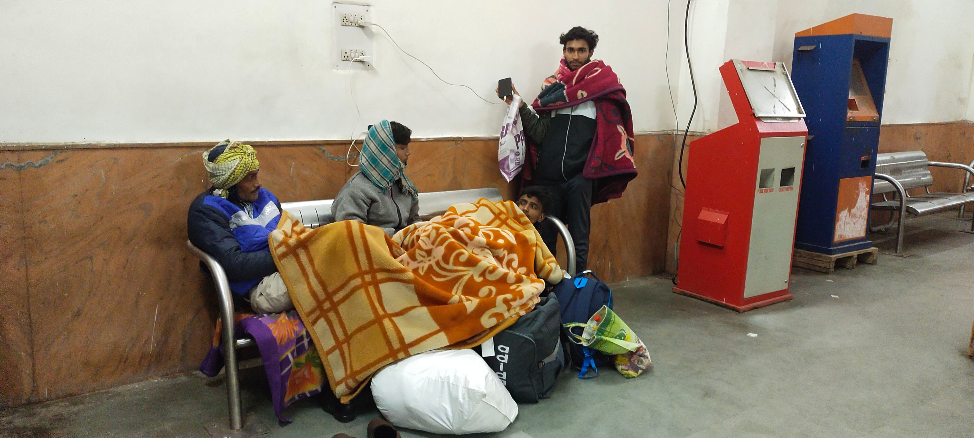 रेलवे स्टेशन पर रात को समय व्यतीत करते बाहर आए यात्री।