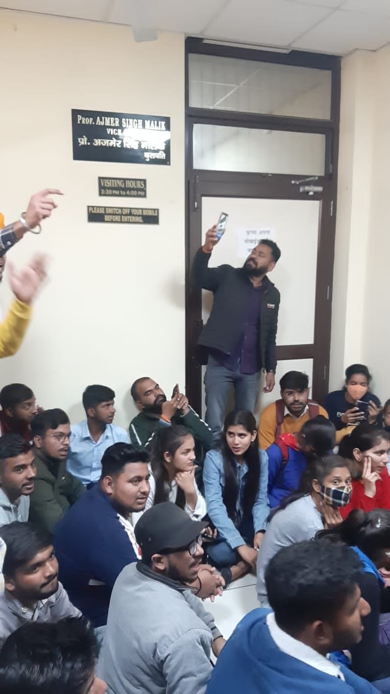 कुलपति कार्यालय के समक्ष धरने पर बैठ रोष प्रकट करते विद्यार्थी।