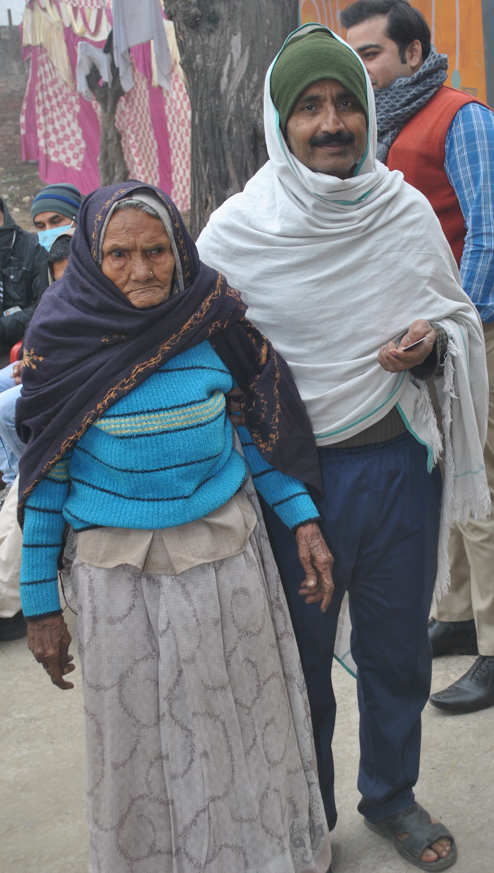 लिसाढ़ में वृद्घ महिला को वोट डलवाने के लिए ले जाता युवक।