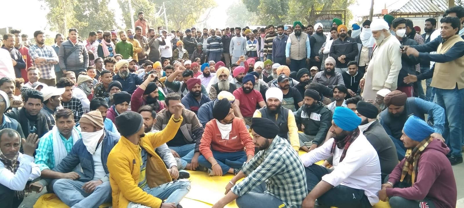 खटीमा के सत्रहमील पुलिस चौकी के सामने खटीमा-पीलीभीत मार्ग पर धरने में बैठकर रोड जाम करते लोग। संव