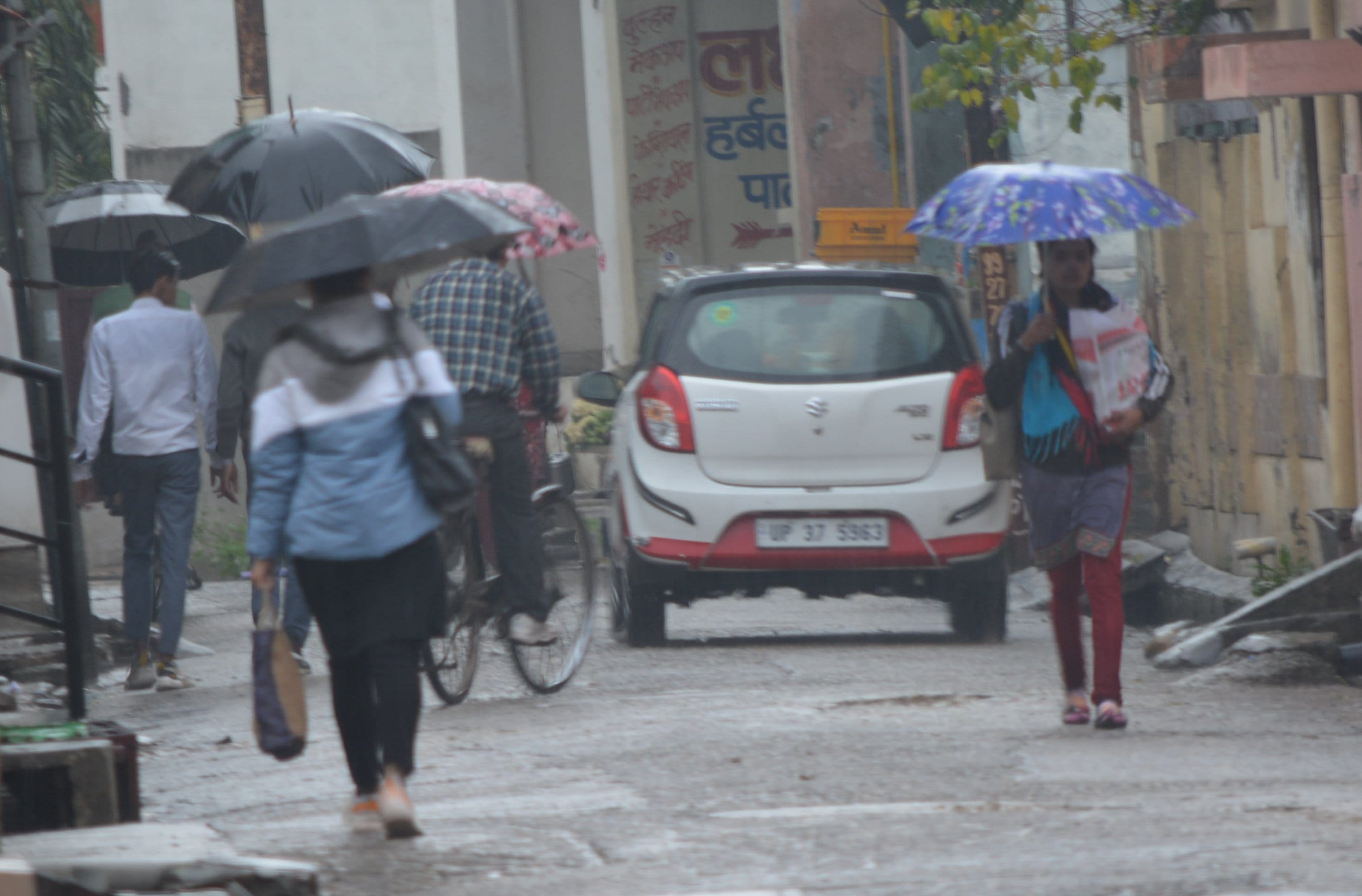 मुजफ्फरनगर में सुबह बारिश में छाता लेकर गंतव्य को जाते राहगीर।